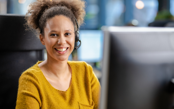 a woman with a headset on working in front of a computer 