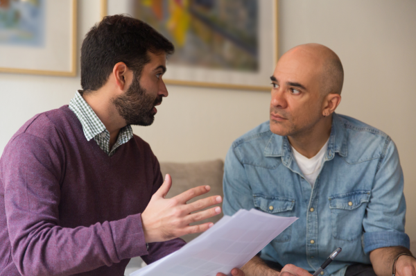 one man is holding a piece of paper explaining something to the person on his right