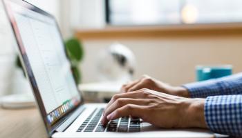 two hands typing on a laptop computer
