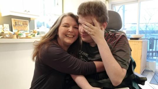 Mom hugs adult son with a disability