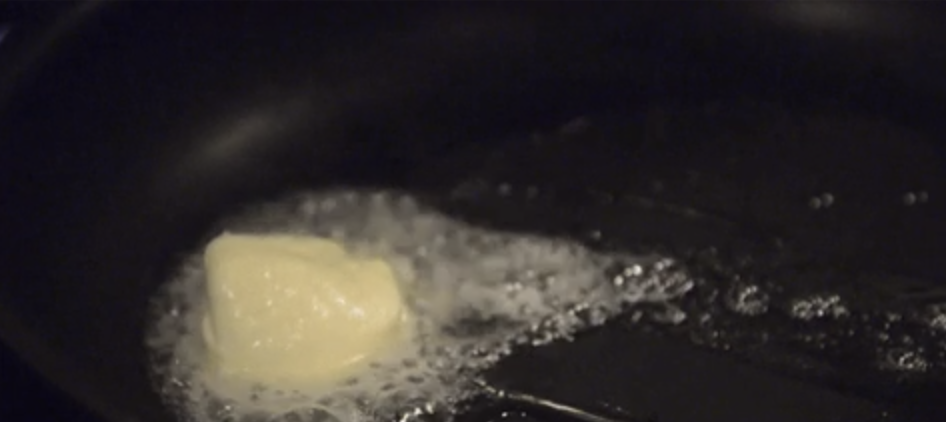 Butter melting in a black frying pan