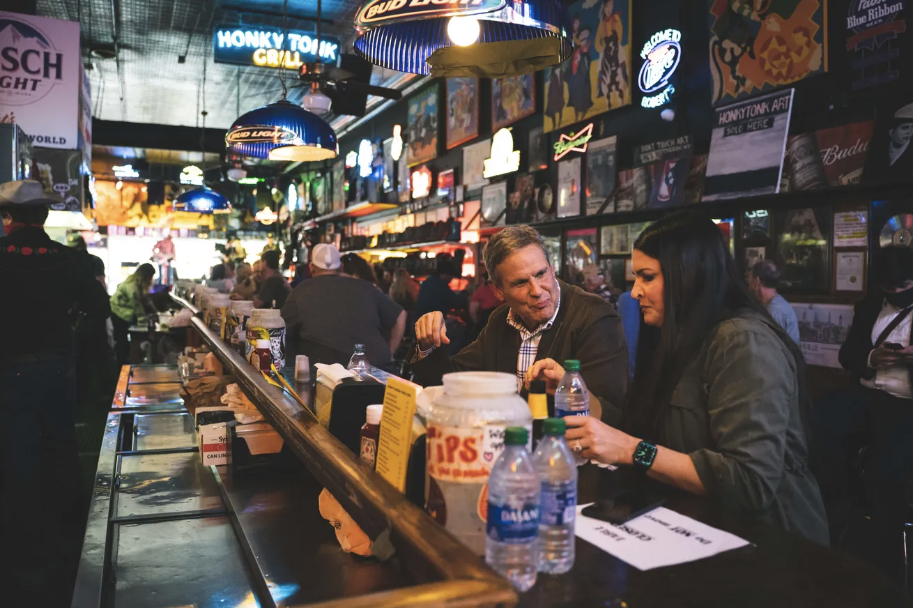 Governor Lee sitting at the bar at Robert's Western World and eating with a constituent